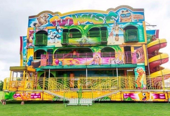 The 3-deck funhouse with its FUN HOUSE name board, painted lion and camel artwork, three levels of balconies and the yellow spiral slide running down its right-hand side