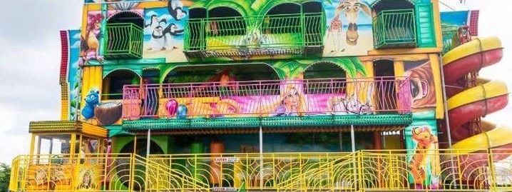 The 3-deck funhouse with its FUN HOUSE name board, painted lion and camel artwork, three levels of balconies and the yellow spiral slide running down its right-hand side