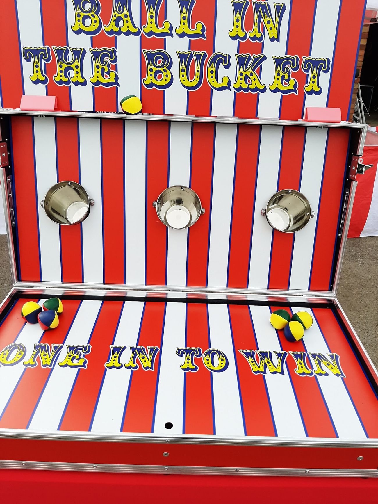 The Ball in a Bucket flight case opened for play, with the three buckets mounted on the striped game board