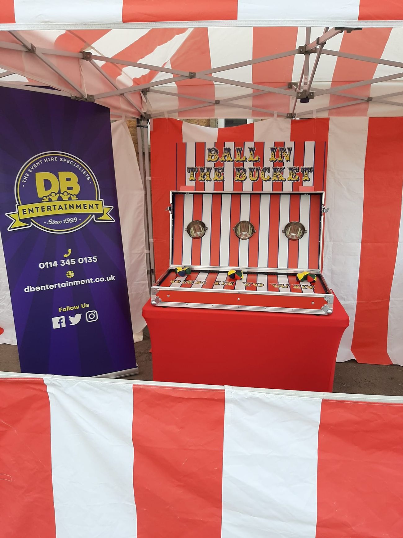 Ball in a Bucket stall under its red and white striped canopy, with the three target buckets mounted on the game board