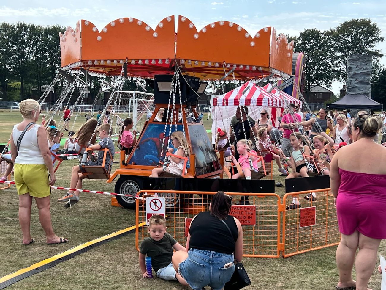 Chair-O-Planes spinning beside a red and white event tent