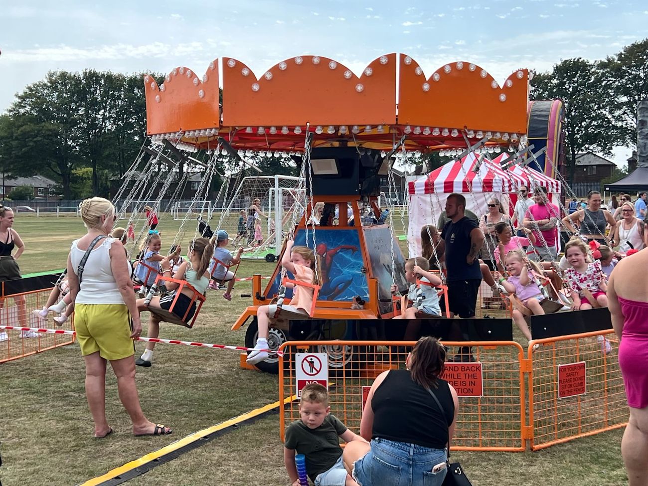 Chair-O-Planes in motion at a summer fete, with children in the swing seats circling the rotating centre