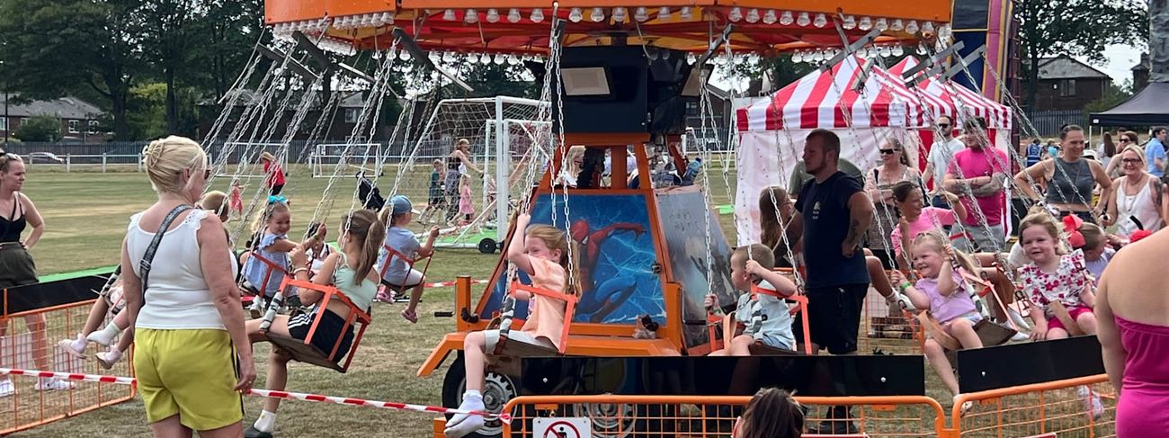 Chair-o-planes ride in motion at a fete, with the trailer and crown canopy in shot