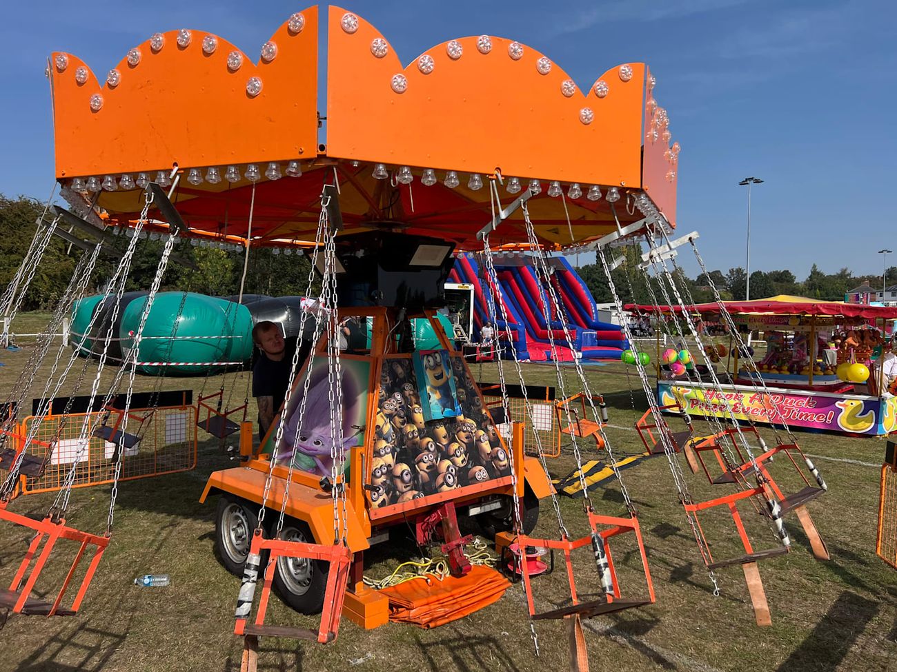 Chair-O-Planes standing at an event with bouncy castles behind it