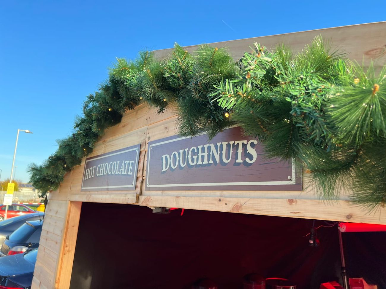 Detail of the garland and signage on a Christmas market stall against a clear sky