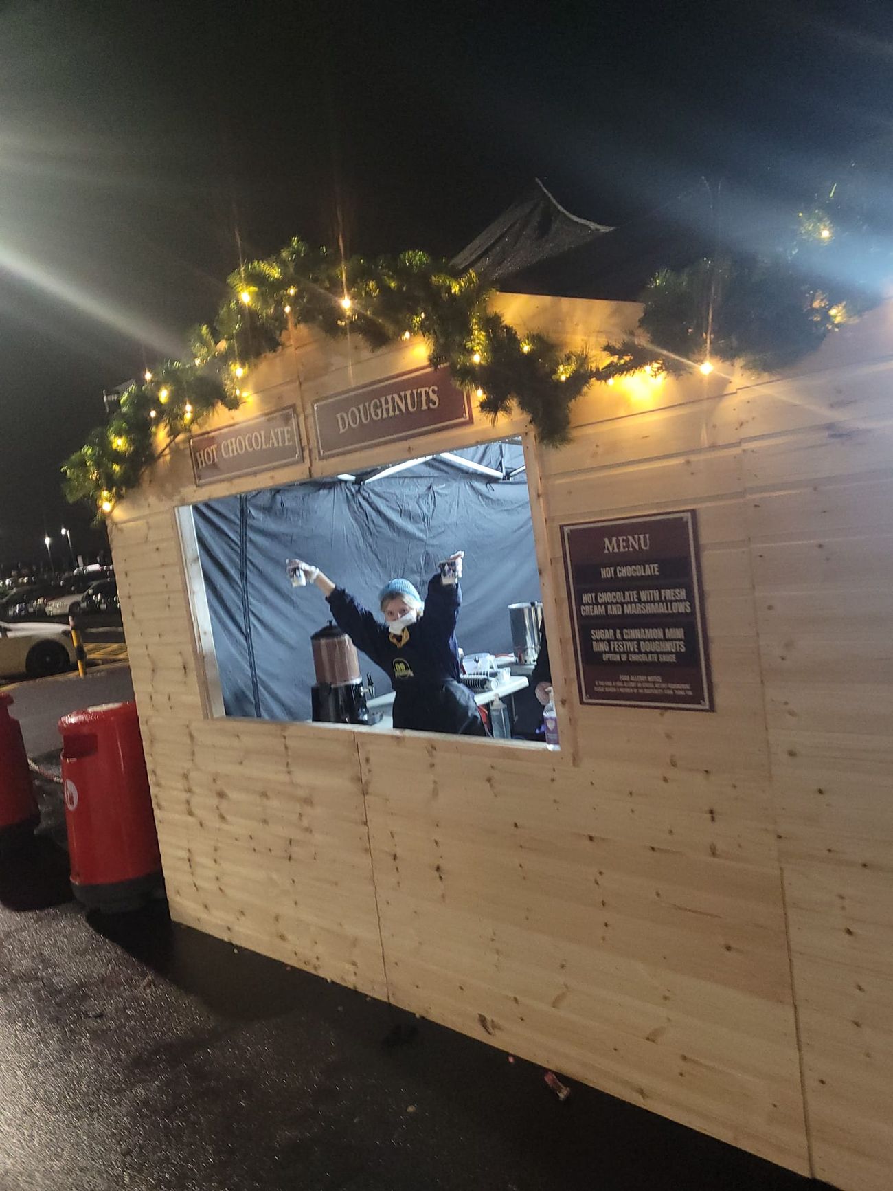 A server raising drinks through the top-hinged serving hatch of a Christmas market stall