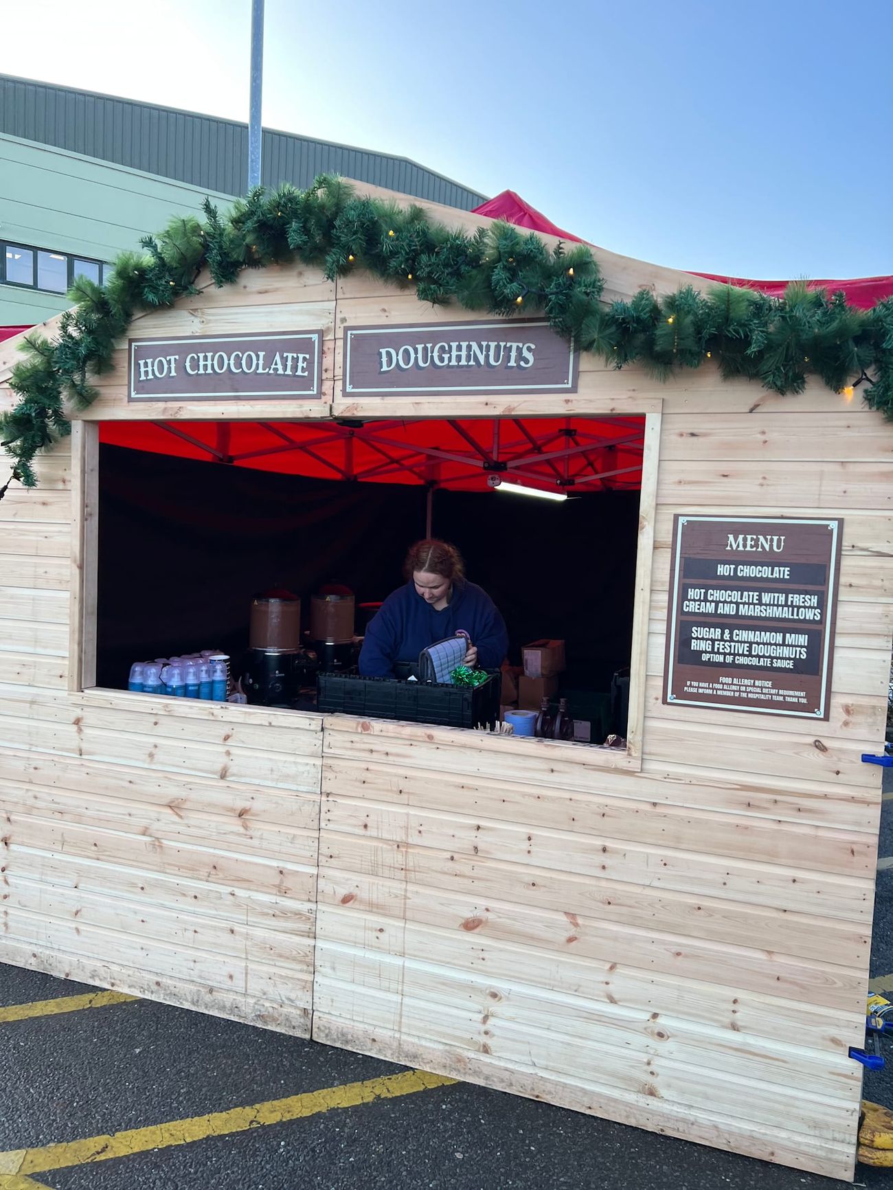 A server preparing hot drinks behind the counter of a Christmas market stall