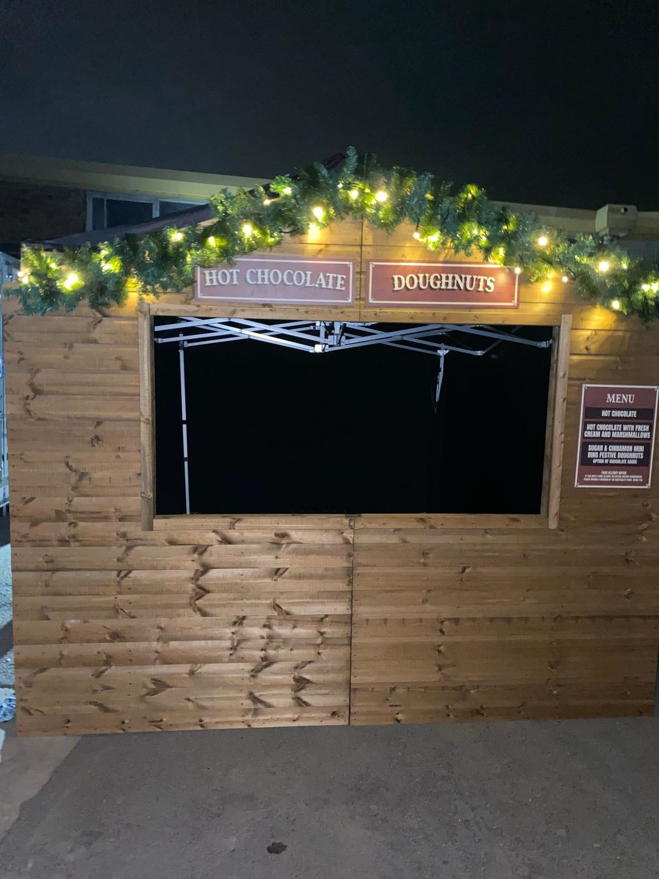Christmas market stall trading after dark with an illuminated garland and lit serving hatch