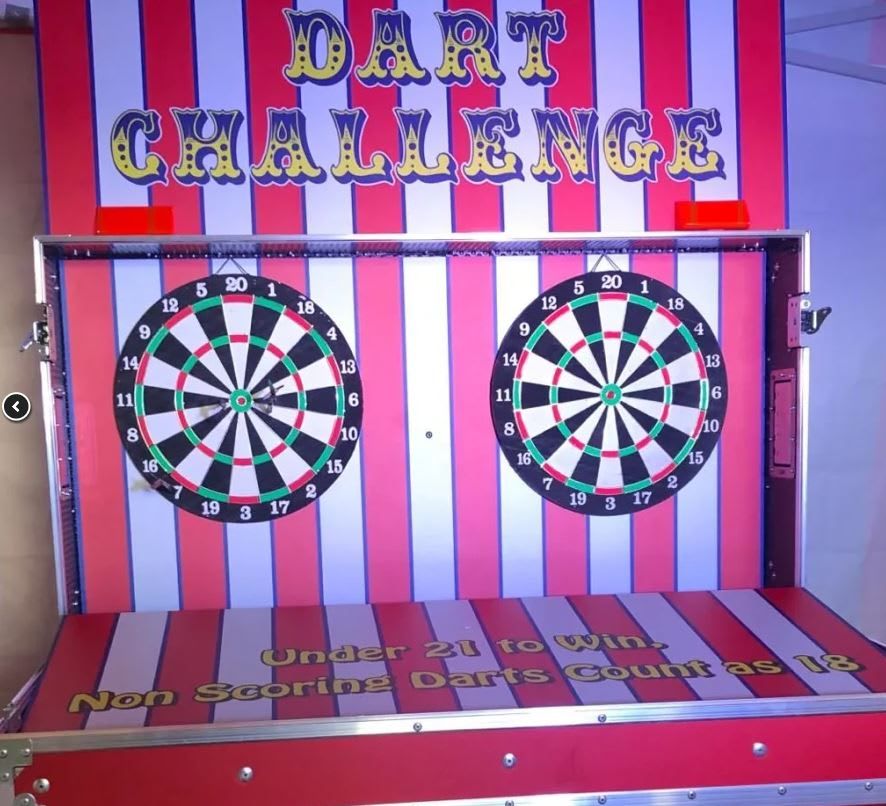 Dart Challenge flight-case stall with its striped backdrop, dartboards and yellow Dart Challenge lettering