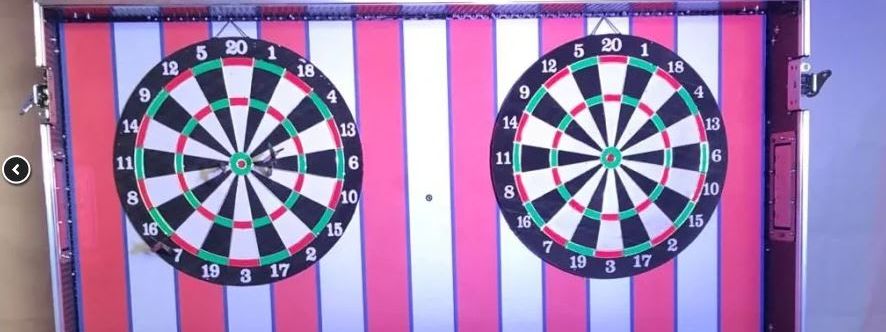 Darts Challenge flight-case stall with its striped backdrop, dartboards and yellow Dart Challenge lettering