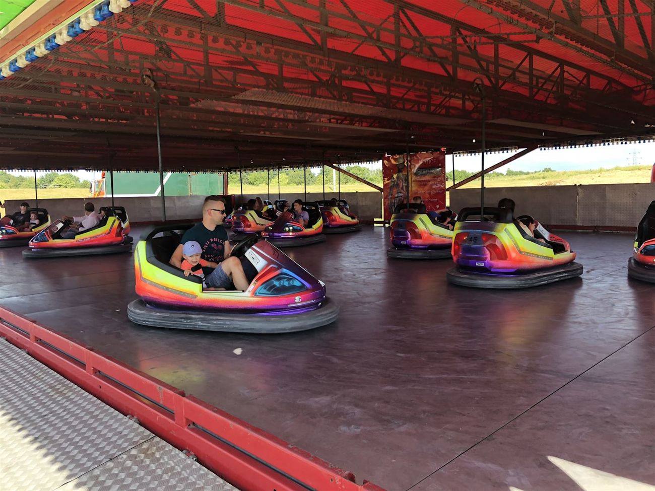 Parent and young child sharing a brightly painted dodgem car on the outdoor rink
