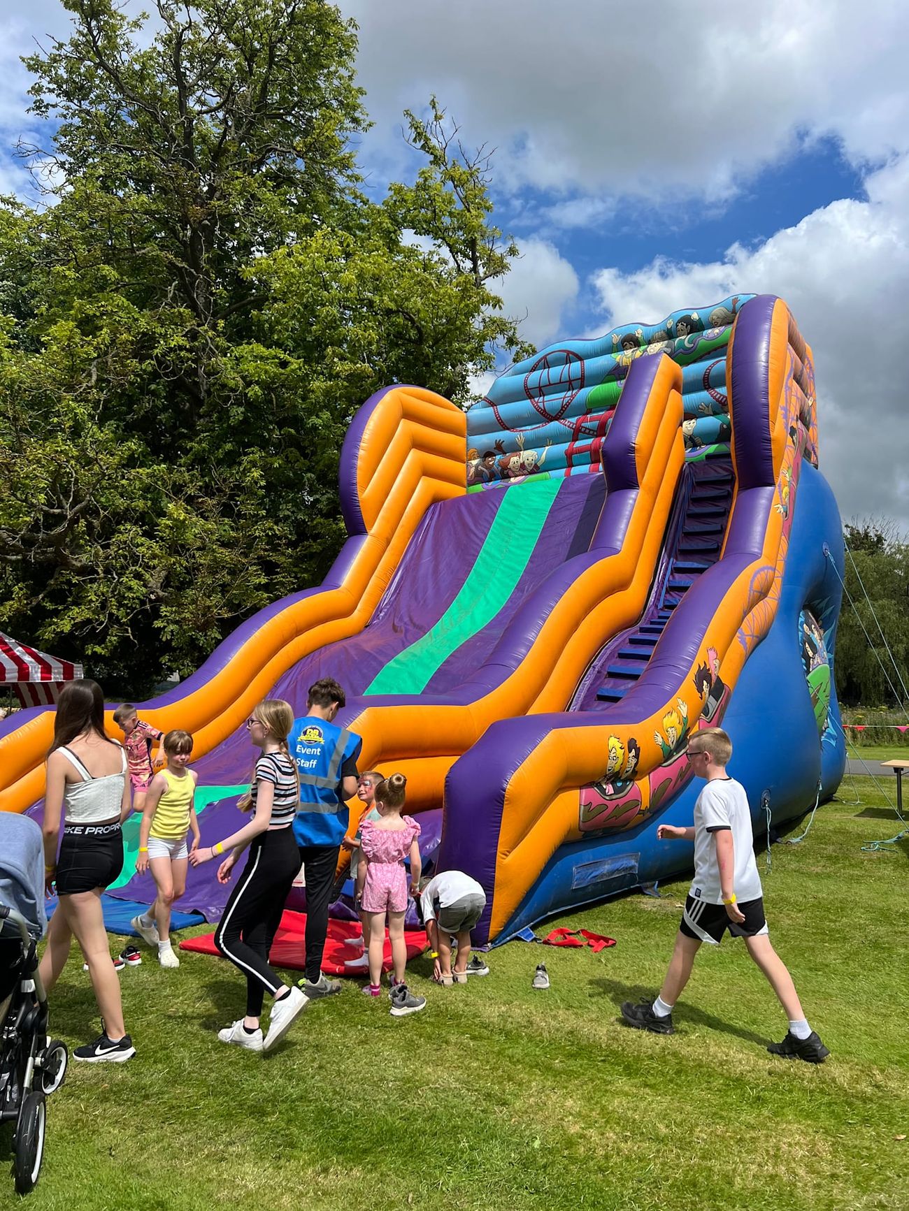 Double-level mega slide set up outdoors, showing the full purple, orange and blue structure with steep stairs and slide lanes