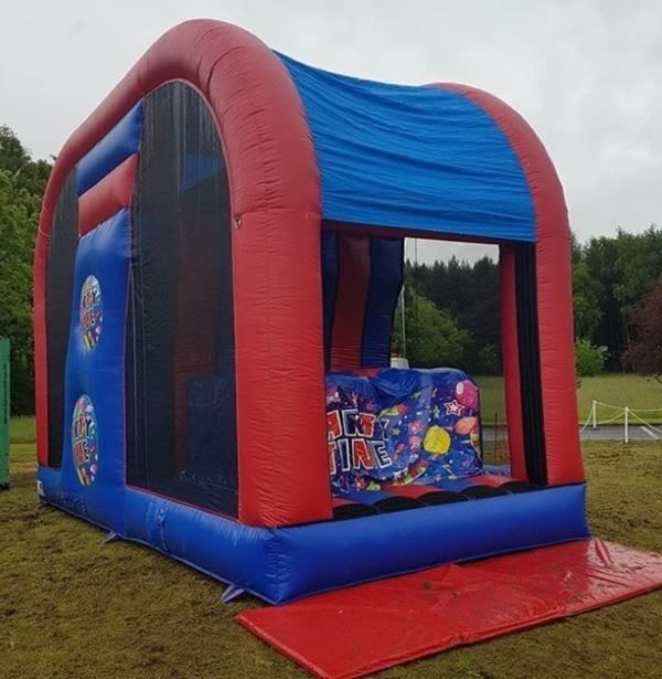 Extreme Base Jump inflatable set up outdoors, showing the red, blue and black structure with its climb and platform