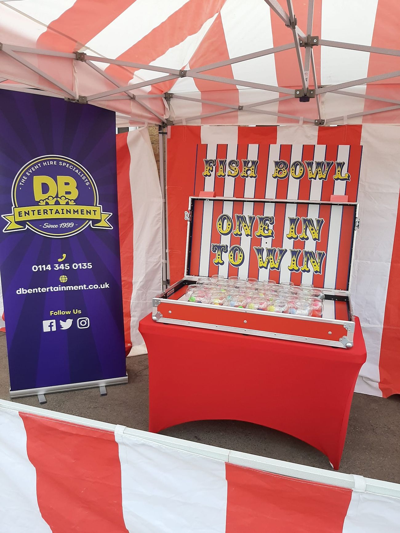 Fish Bowl Challenge stall under its red and white striped canopy, with a grid of glass fish bowls mounted on the game board