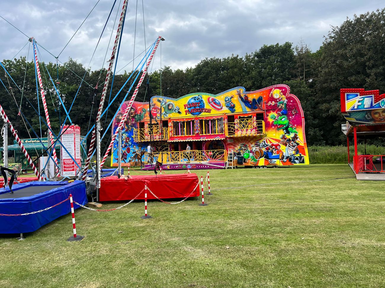 The funhouse frontage showing the painted character panels, the two balcony walks and the entrance ramp, with bungee trampolines in the foreground