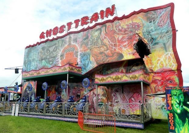 Daylight view of the Ghost Train frontage, fenced loading deck, raised figures and separate photo booth at the right-hand end