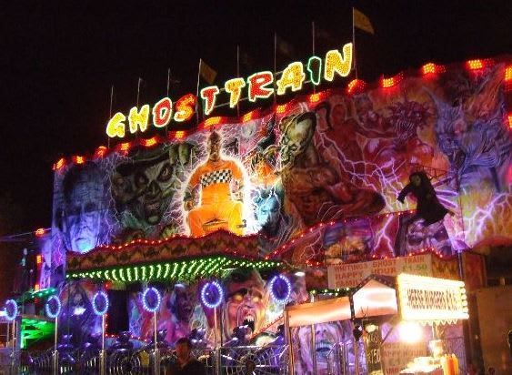 Upper Ghost Train frontage and loading deck illuminated at night with bulb lettering and circular canopy lights