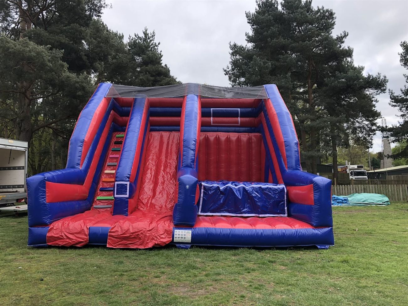 Giant Base Jump Slide inflatable set up indoors, showing the full red and blue structure with the climb, slide and base jump platform
