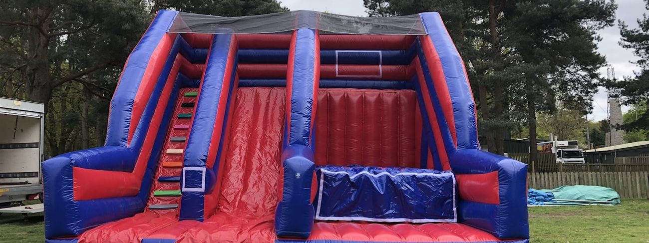 Giant Base Jump Slide inflatable set up indoors, showing the full red and blue structure with the climb, slide and base jump platform