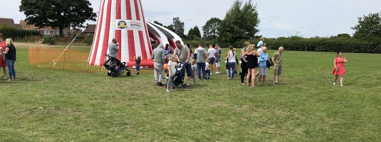 Giant helter skelter with a crowd gathering around it at a community fete