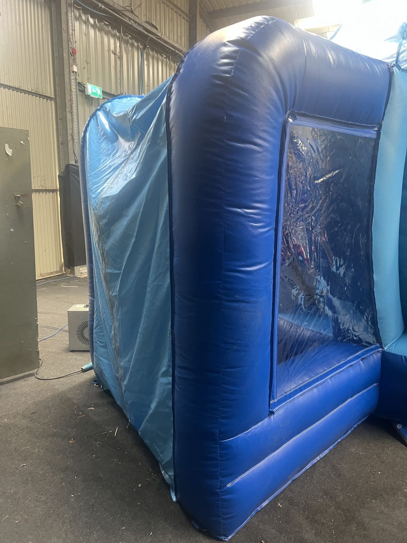 Side view of the giant snow globe's blue inflatable base and clear window with the external blower unit