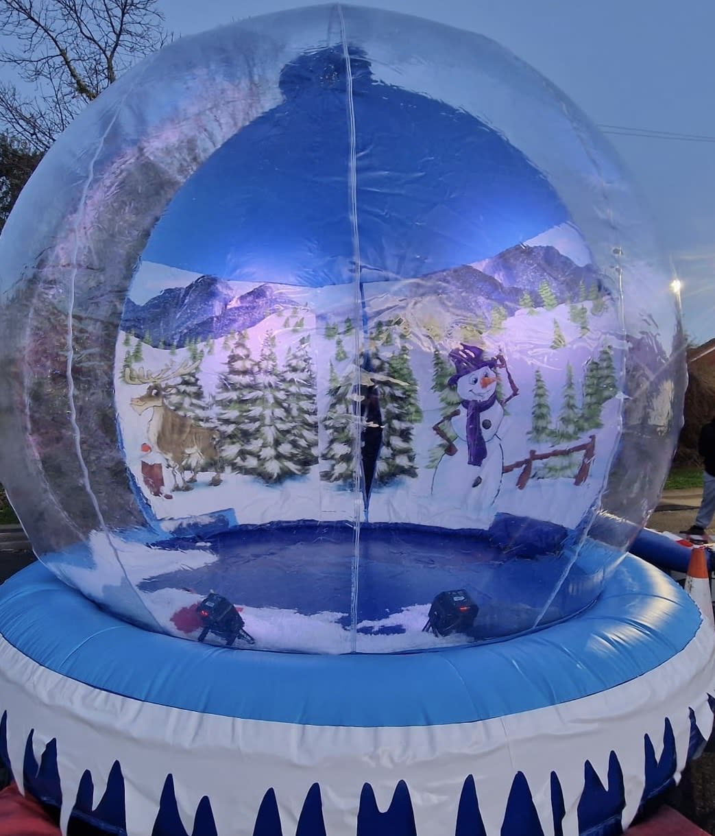 Front-on view of the giant snow globe's complete painted interior with mountains, pine trees, reindeer and snowman