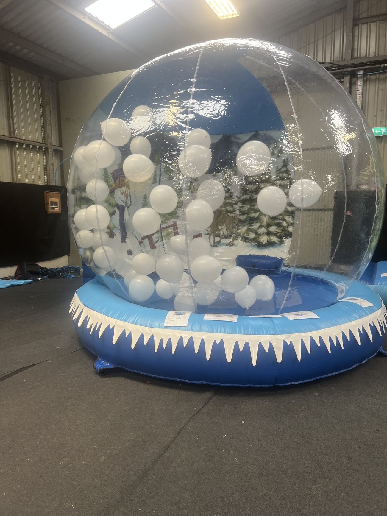 The giant snow globe interior filled with white balloons, with the painted backdrop visible behind