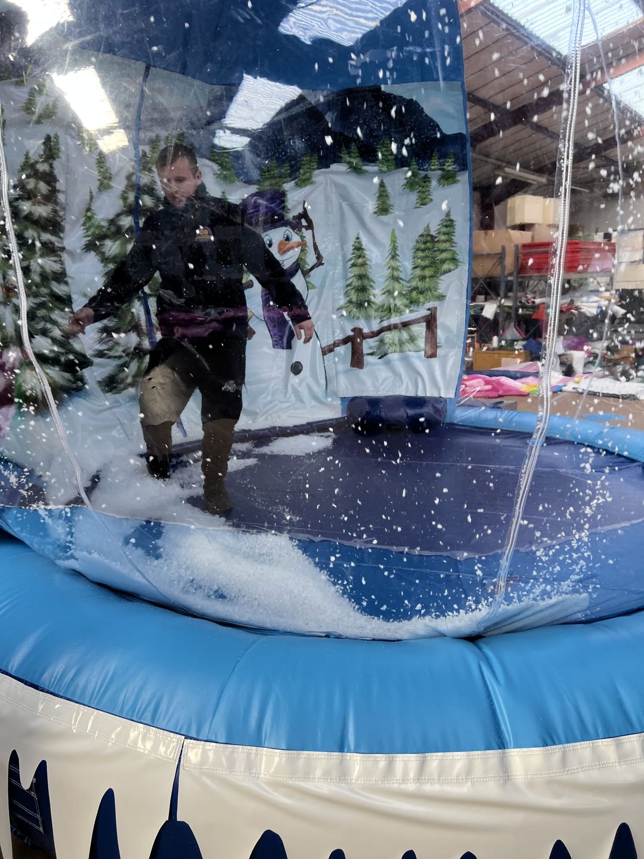 A supervisor inside the giant snow globe with artificial snow swirling around the painted winter scene
