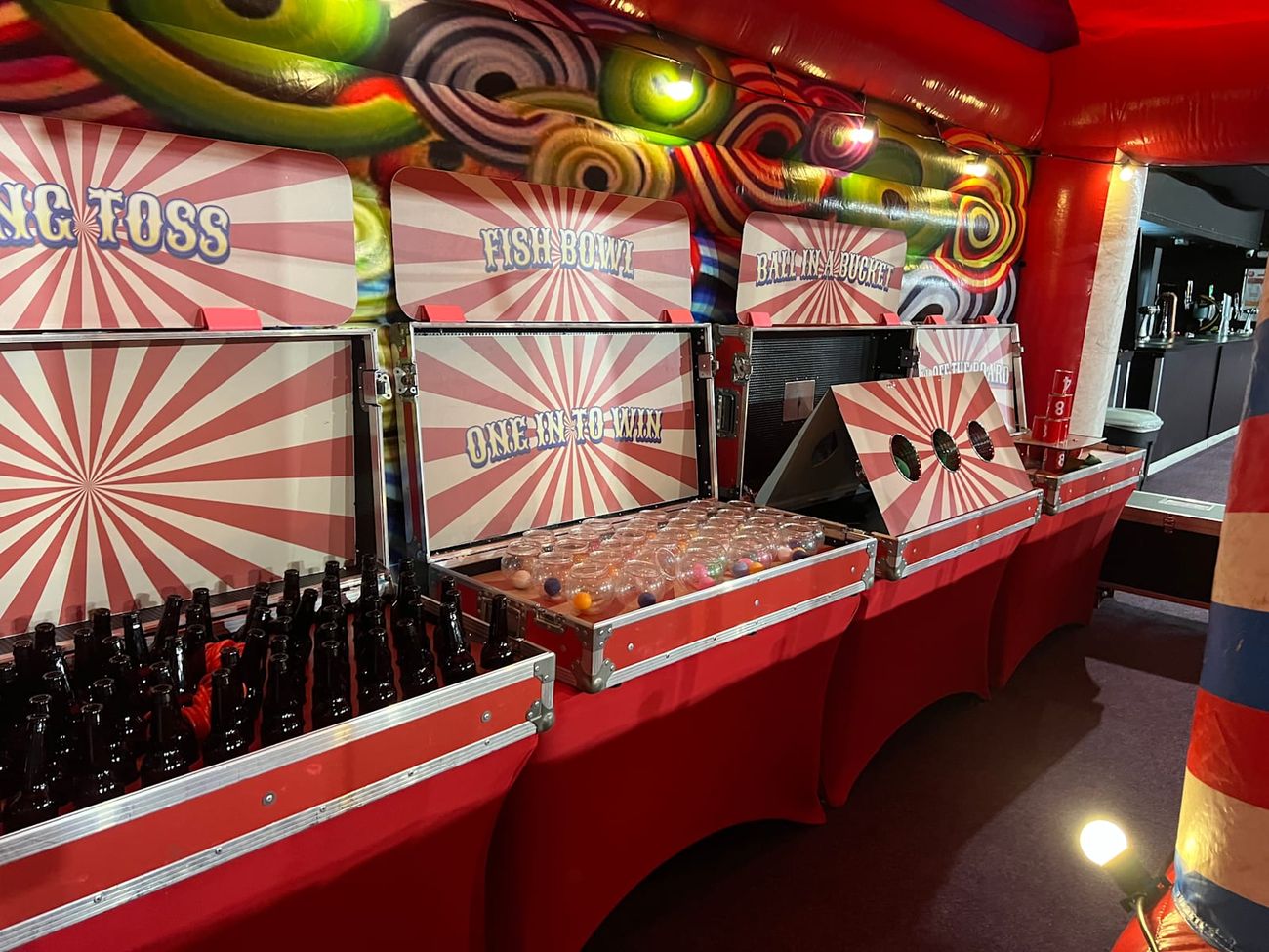 The four Grand Carnival game stations lined up inside the stall, each flight case open to show its game
