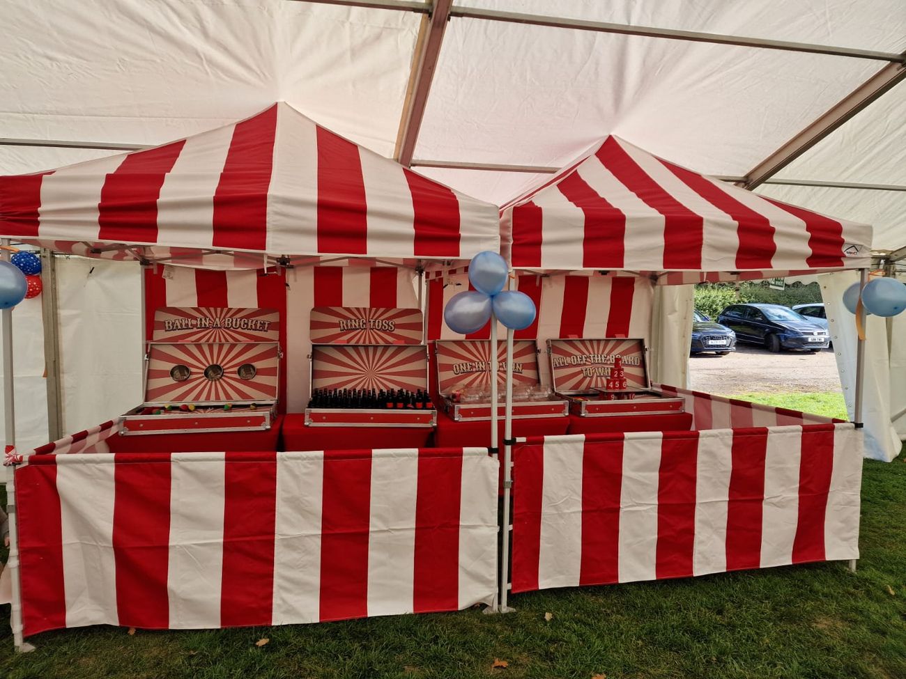 Hook-a-Duck booth set up inside an event marquee, showing its double-peaked canopy and striped frontage