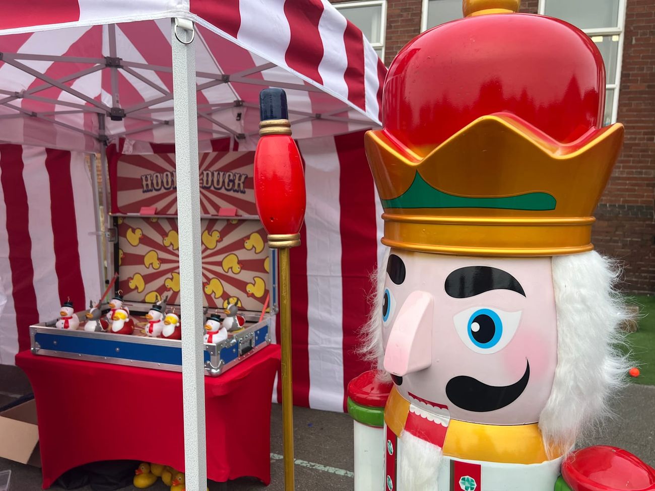 A giant nutcracker standing alongside the Hook-a-Duck stall at a festive event