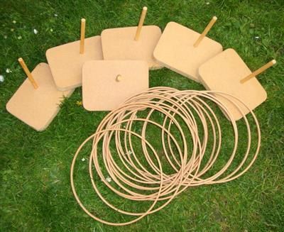 Hoopla kit laid out on grass, with wooden blocks and pegs to aim at and a pile of rattan throwing rings