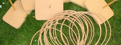 Hoopla kit laid out on grass, with wooden blocks and pegs to aim at and a pile of rattan throwing rings
