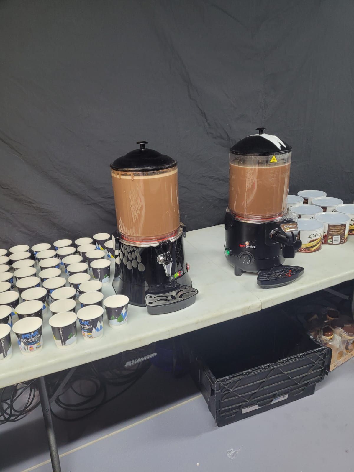 Commercial hot chocolate dispensers on a serving table, ready to pour for guests at an event