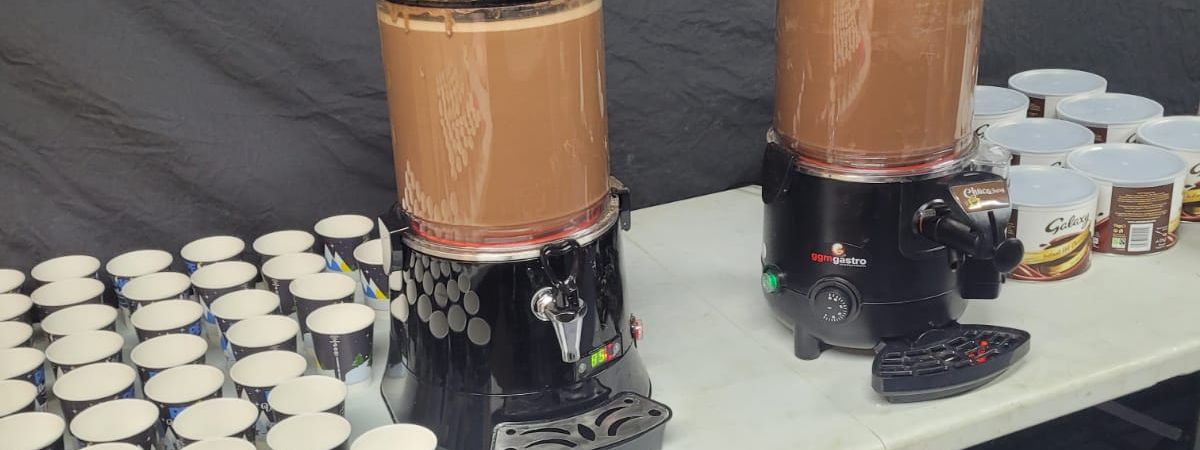 Commercial hot chocolate dispensers on a serving table, ready to pour for guests at an event