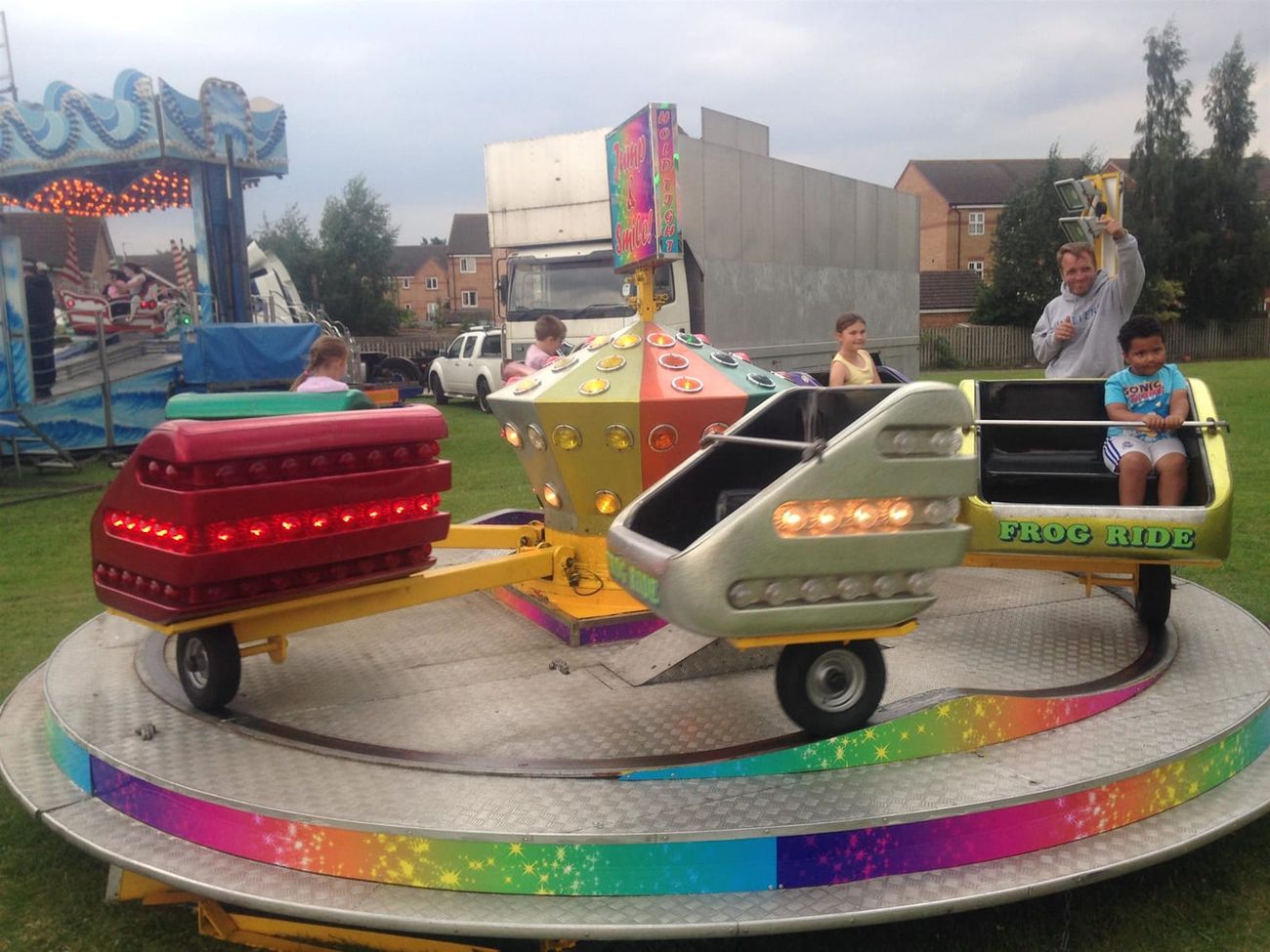 Jump and Smile children's ride with frog-themed cars on a circular platform with a rainbow edge and the Jump and Smile sign
