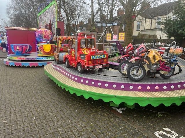 The Juvenile Formula's vehicle carriages on the green scalloped base, with the tea cup ride set up behind it