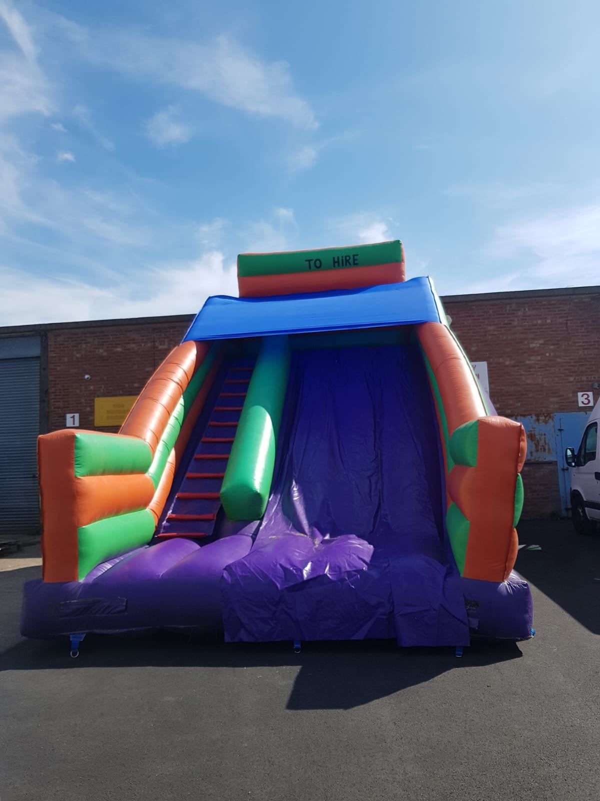 Mega Purple Slide inflatable set up outdoors, showing the purple and multi-coloured structure