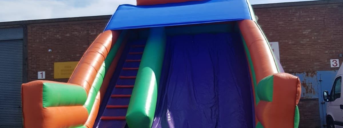 Mega Purple Slide inflatable set up outdoors, showing the purple and multi-coloured structure with its climb and slide