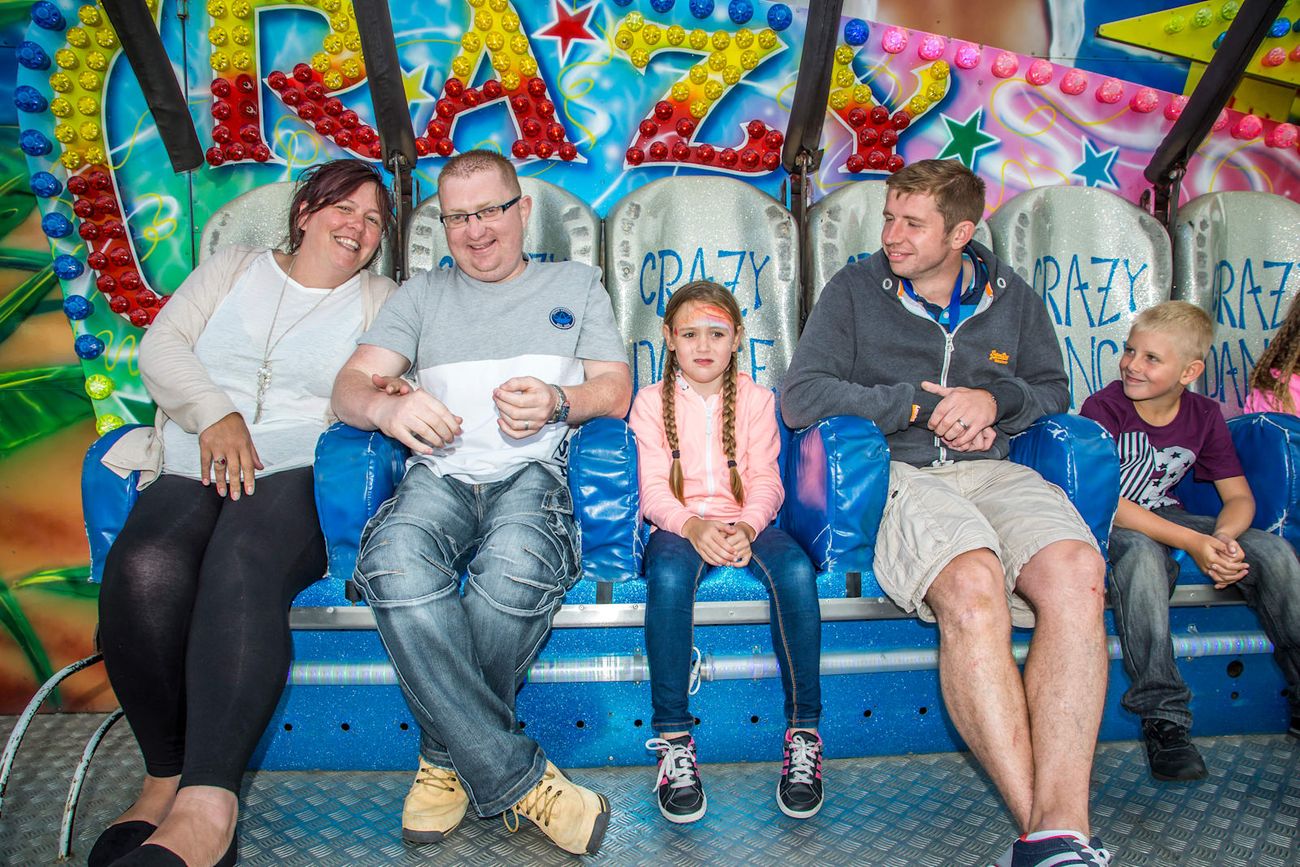 Adults and children seated across part of the Miami ride bench with individual seats and overhead restraints