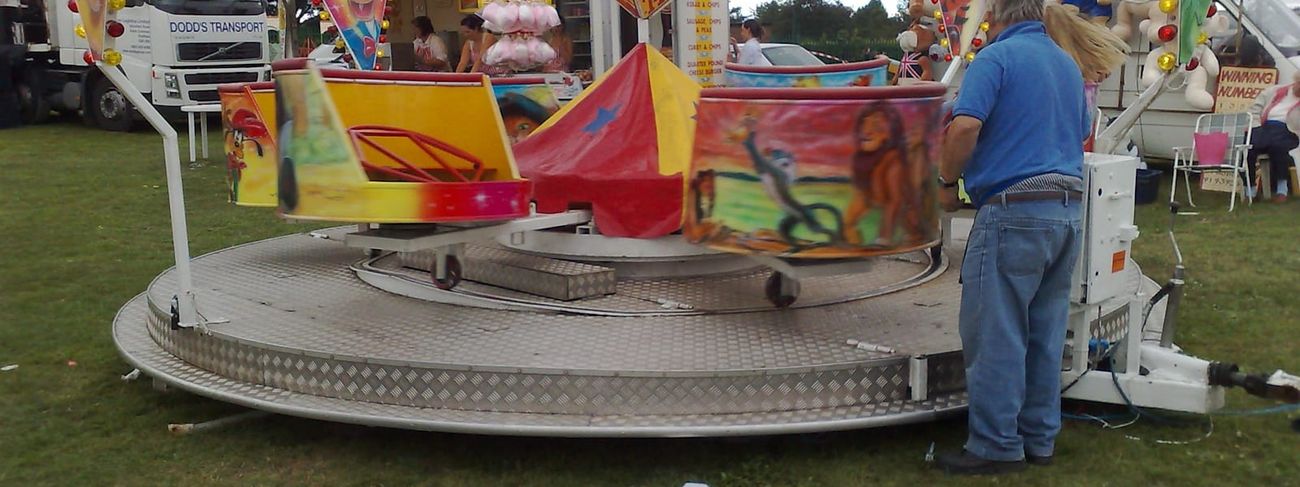 Juvenile mini waltzer ride set up on a grass field with its tubs and rainbow edge