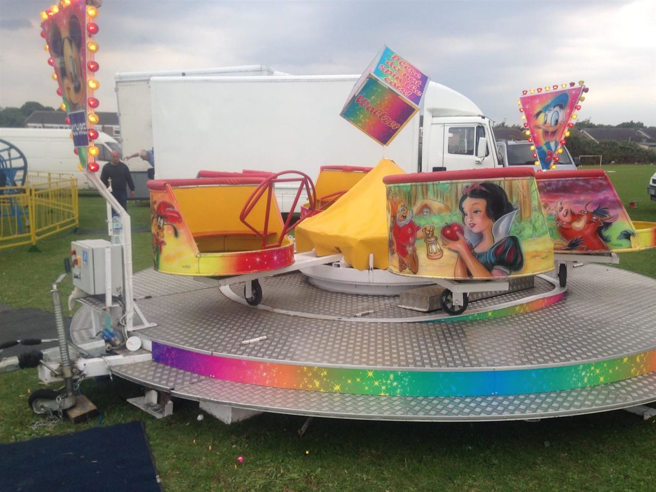 Mini waltzer children's ride with spinning tubs on a circular platform with a rainbow-edged skirt