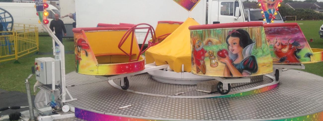 Mini waltzer children's ride with spinning tubs on a circular platform with a rainbow-edged skirt