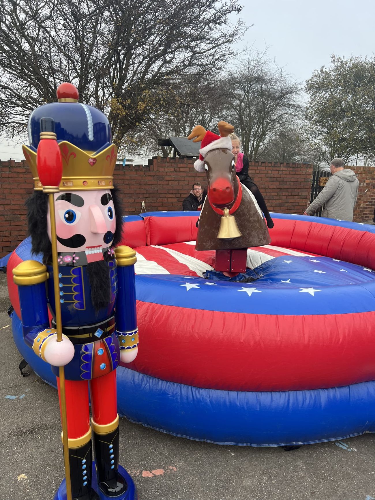 A nutcracker prop standing beside the inflatable rodeo reindeer ride