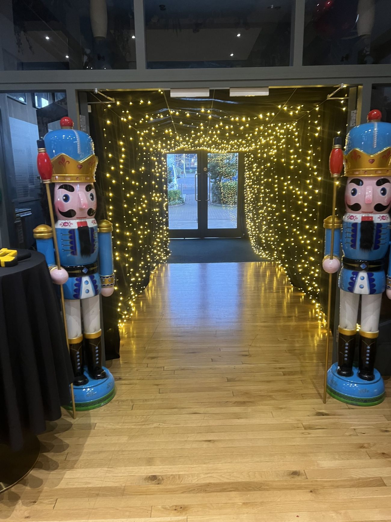 A pair of giant nutcracker props flanking a fairy-light entrance archway