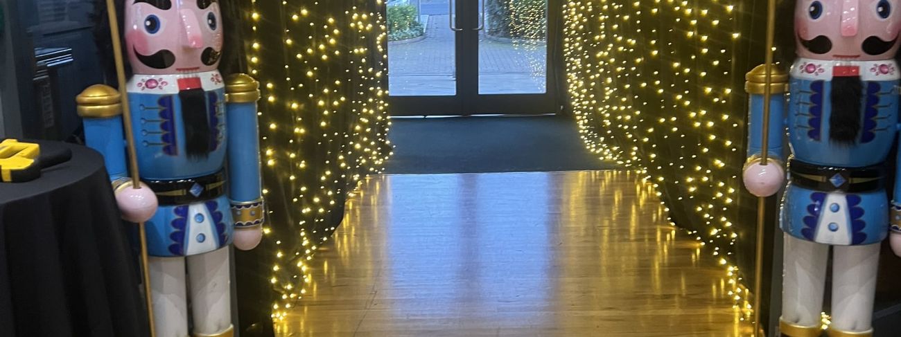 A pair of giant nutcracker props flanking a fairy-light entrance archway