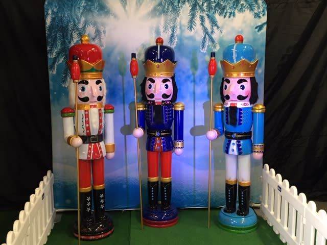 An indoor Nutcracker Trail display with snowy backdrop and white fencing