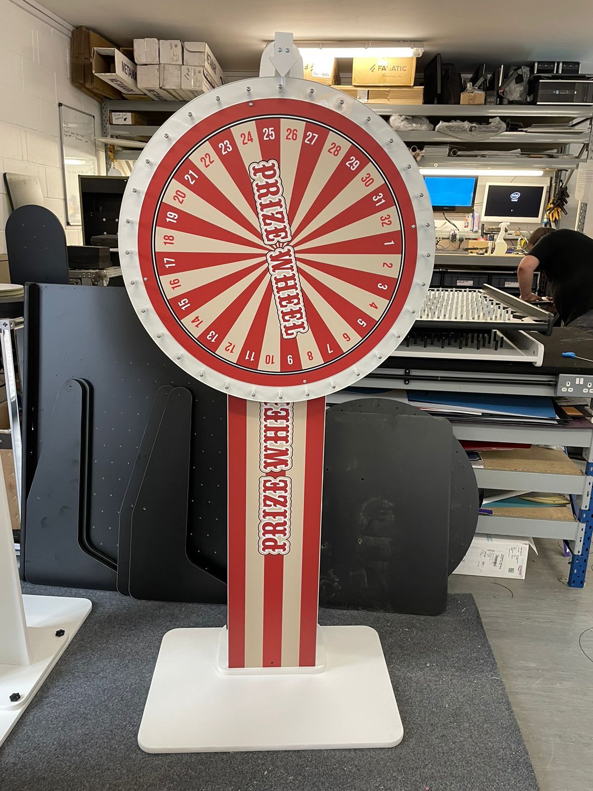 Classic carnival-style Prize Wheel with its ornate gold banner, red and white segments and bulb-lit rim