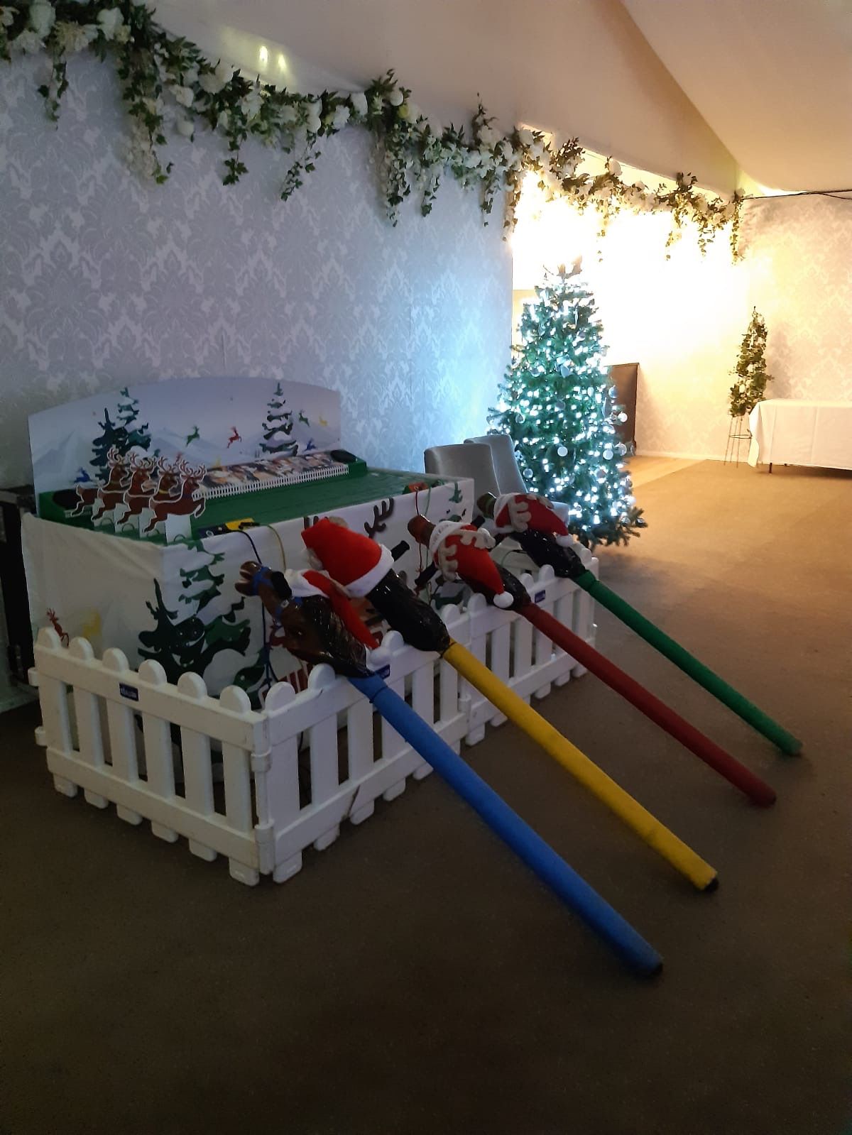 The full Reindeer Racing setup with four controls and a lit Christmas tree with festive decorations