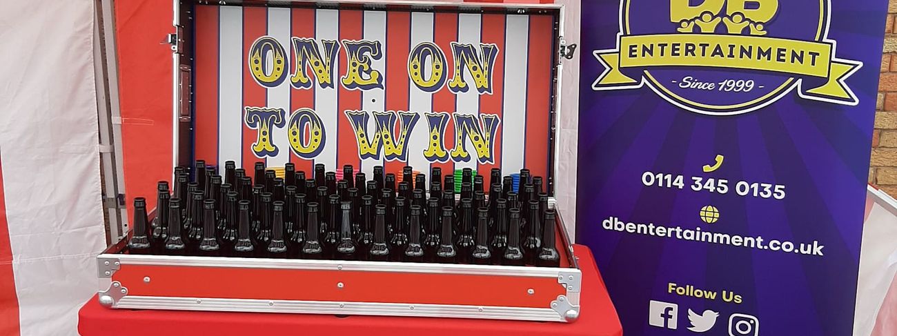 Ring Toss stall under its red and white striped canopy, with bottles packed into the flight case and rings ready to throw